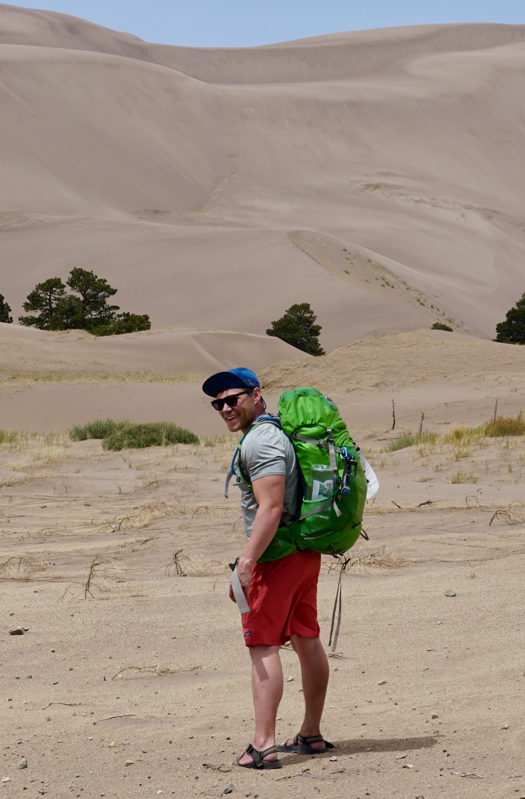 Steven hiking in the desert with a green backpack